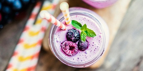 Verre de smoothie, framboises et myrtilles. Des pailles sont dans le verre.
